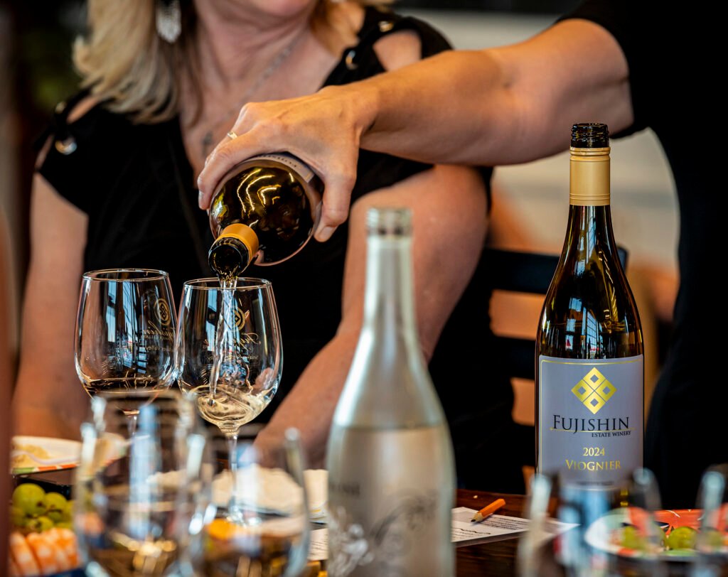 woman pouring white wine into two wine glasses