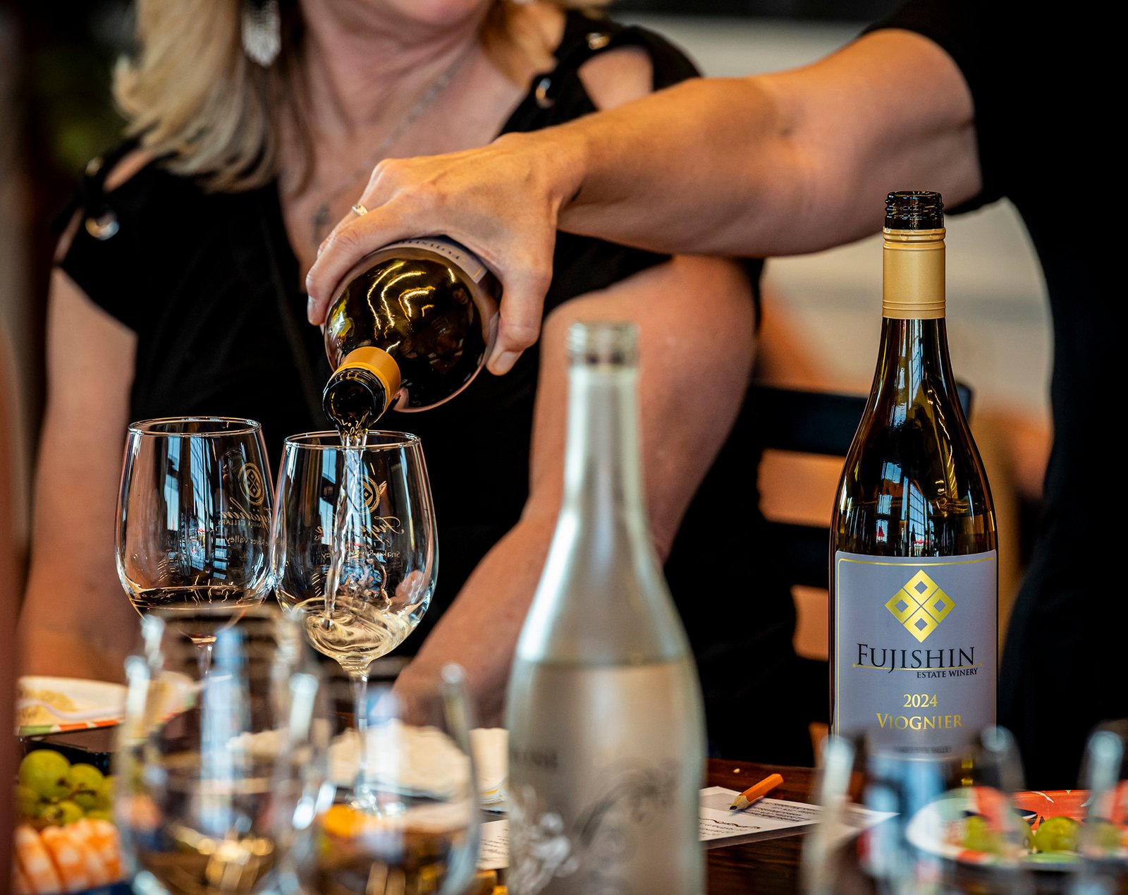 woman pouring white wine into two wine glasses